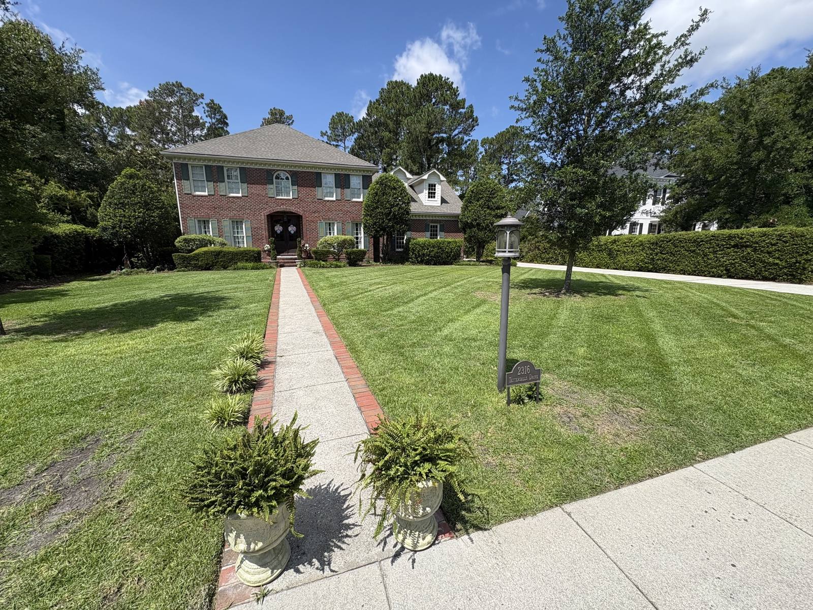 Mowing stripes and a brick walk in front of a colonial home